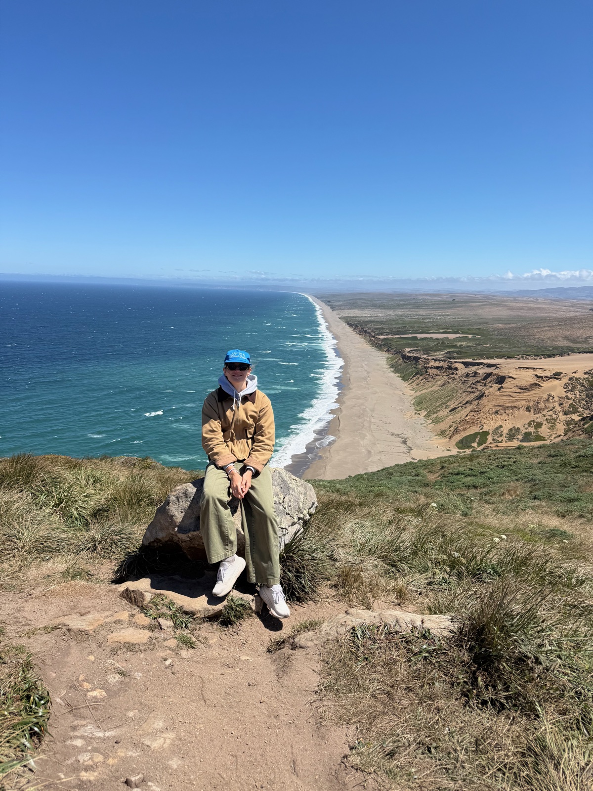 Aida sitting on a rock above the Point Reyes coastline